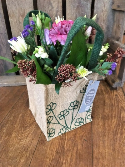 Natures Choice - Handpicked pink, cream purple and green flowers arranged in foam and presented in a hessian bag.

Each and every display is one-of-a-kind, created by an artisan florist using the most beautiful and fresh stems available on the day so, whilst your gift may look different to the one pictured, we do guarantee that your specific arrangement will be fresh, beautiful and that your recipient will love it!