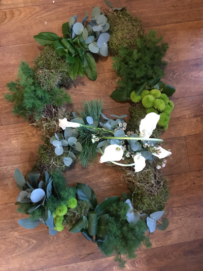 Double Heart - Double heart funeral tribute made in a woodland style with moss and twigs along with green foliages and flowers.